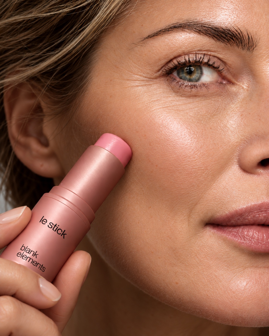 Close-up of pink Le Stick balm being applied to a cheek with natural skin texture